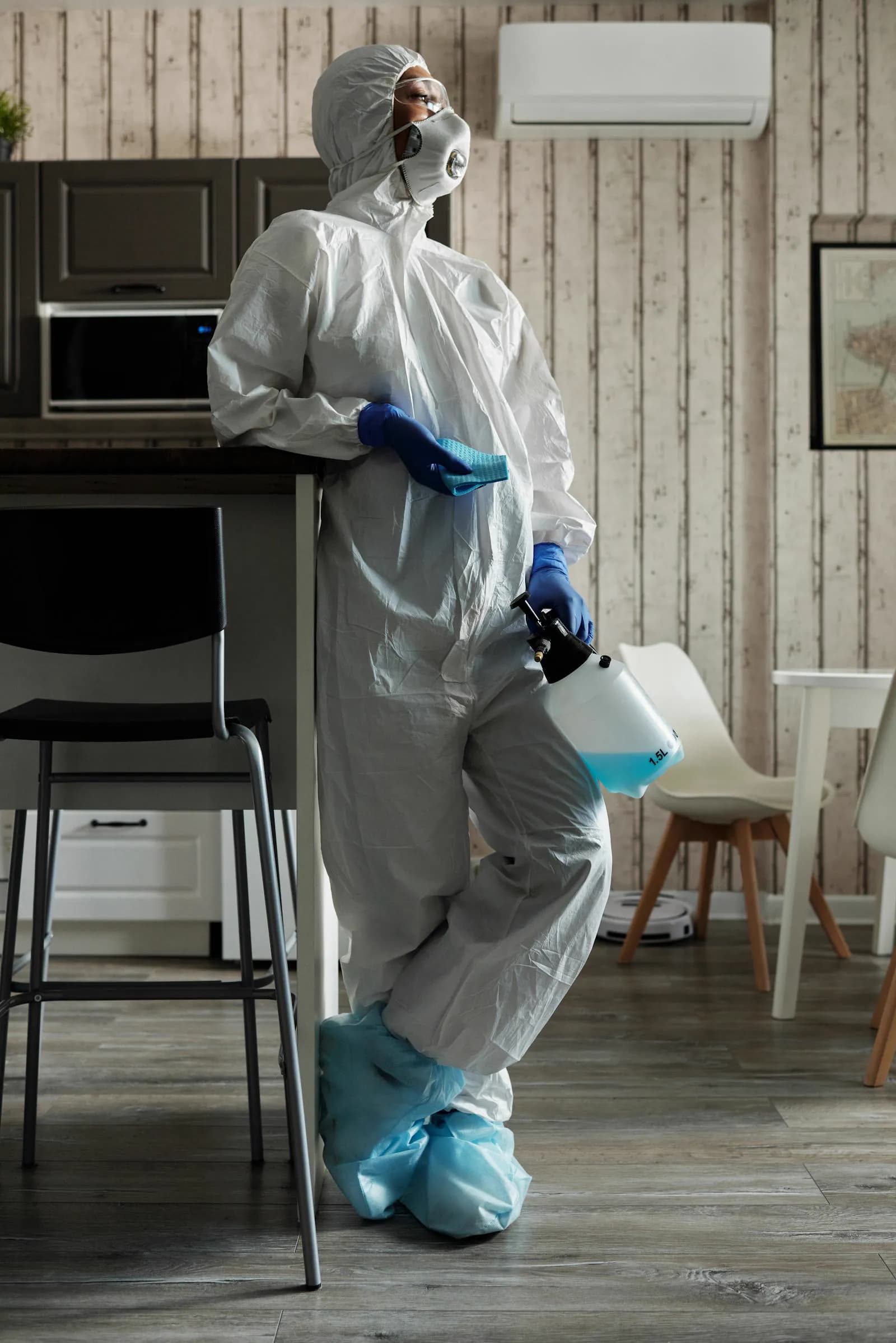 Technicien en EPI Tyvek pulvérisant un produit désinfectant virucide