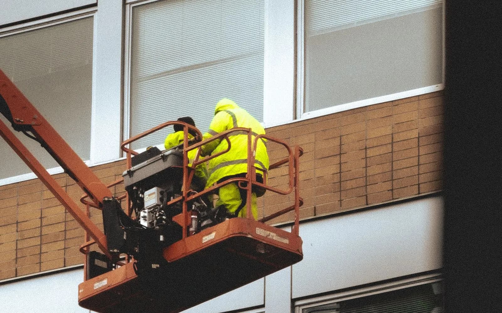 Deux techniciens sur une nacelle élévatrice intervenant sur une façade d'immeuble